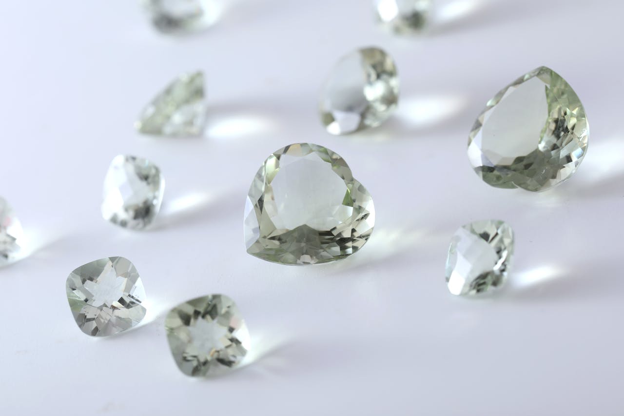 Close-up of multiple green gemstones on a reflective white surface.